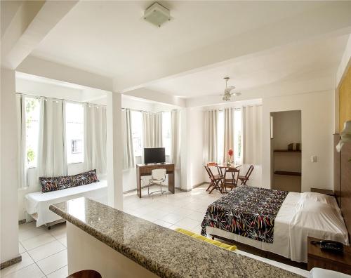 um quarto com uma cama e uma sala de estar em Caiçara Flats em Cabo Frio