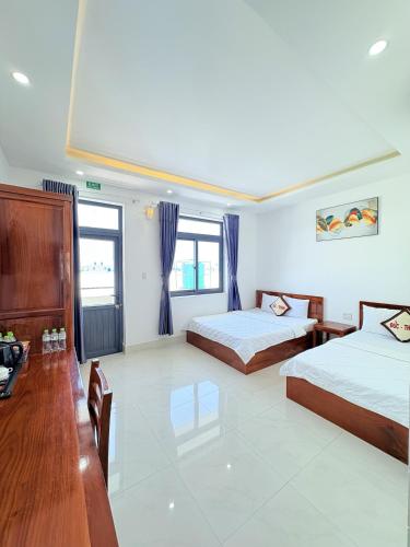 a bedroom with two beds and a table and a desk at ĐỨC THẠNH HOTEL in Rạch Giá