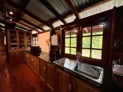 eine Küche mit Spüle und zwei Fenstern in der Unterkunft Doungploy BaanruenThai Homestay in Ban Hua Phrong