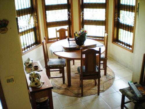 a dining room with a table and chairs and windows at Refúgio do Azzi in Monte Verde