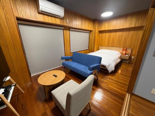 a small room with a bed and a blue chair at Kokusai Towns Inn in Naha