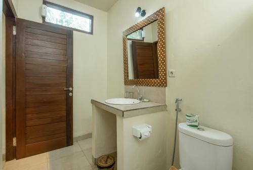 a bathroom with a toilet and a sink and a mirror at Yessi House in Ubud