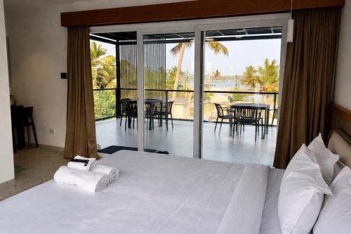 a bedroom with a white bed with a view of a patio at The Cove Beach Resort in Cochin