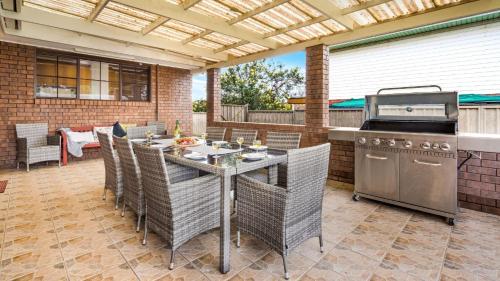 an outdoor patio with a table and a grill at The Callala Hideaway in Callala Beach