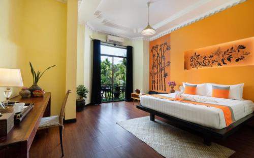 a bedroom with a bed and a table and a desk at Central Indochine d'Angkor Hotel in Siem Reap