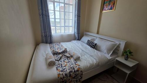 a bedroom with a white bed with a window at Mina Luxe Machakos in Machakos