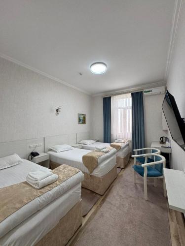 a hotel room with four beds and a television at Muxlis Hotel in Tashkent