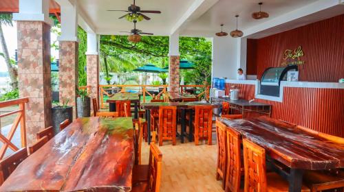a restaurant with wooden tables and wooden chairs at The Lei's Hotel and Beach Resort in Mercedes