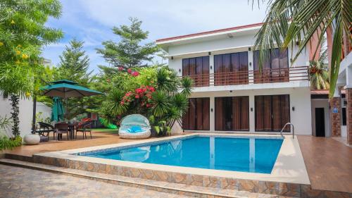 a villa with a swimming pool in front of a house at The Lei's Hotel and Beach Resort in Mercedes