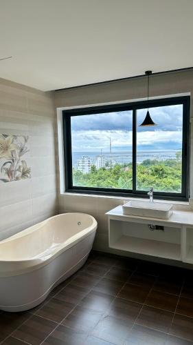 a bathroom with a tub and a sink and a window at Rosso Sky Villa Phu Quoc in Phú Quốc