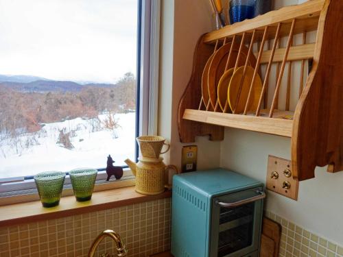 a kitchen with a window with a view of snow at Sauna Paistaa in Sobetsu