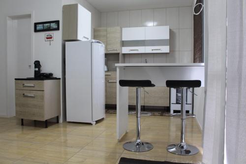 a kitchen with a white refrigerator and two bar stools at Palhoça Praia Ponta do Papagaio SUNSET Apto 102 in Palhoça