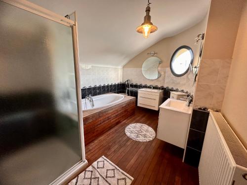 a bathroom with a tub and a sink and a shower at Villa du Siéck bord de mer piscine 14 P in Santec