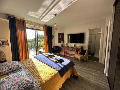a bedroom with a bed and a desk and a television at Villa du Siéck bord de mer piscine 14 P in Santec