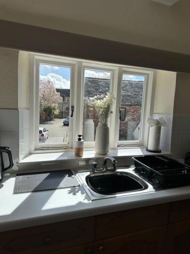 a kitchen counter with a sink and two windows at Charming 3 Bedroom High St Apartment in Much Wenlock