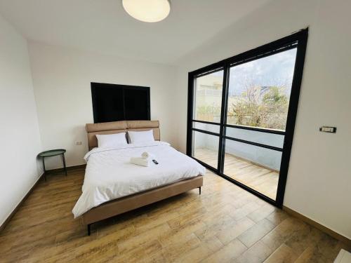 a bedroom with a bed and a large window at Villa Sol Aviv - וילה מושלמת עם בריכה פרטית למשפחות וקבוצות בנתיבות in Netivot