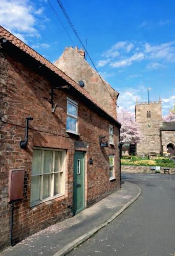 a brick building with a green door on a street at The Old Shop at Savile House - Sherwood Forest in Ollerton