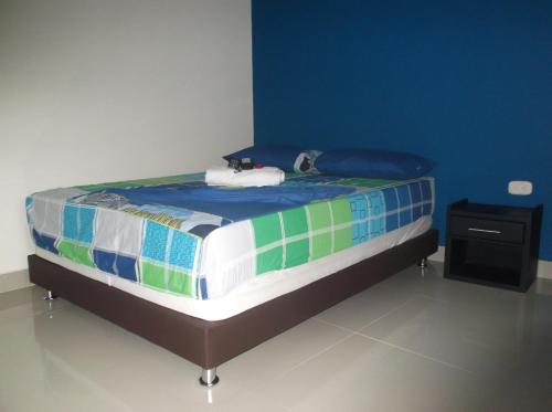 a bed in a room with a blue wall at Hotel Monarca Putumayo in Orito