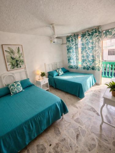 two beds in a room with green sheets at Suites Acapulco Real in Acapulco
