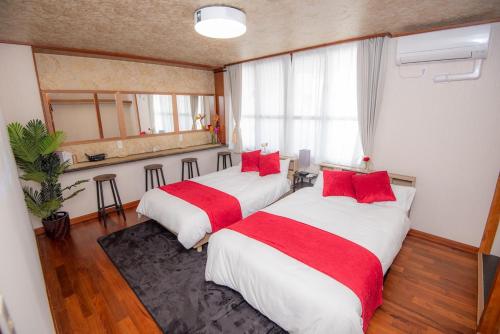 two beds in a hotel room with red pillows at TIDA house urasoe in Urazoe