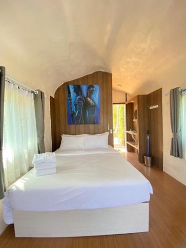a bedroom with a large white bed with a painting on the wall at Olympus khaoyai in Ban Nong Makha