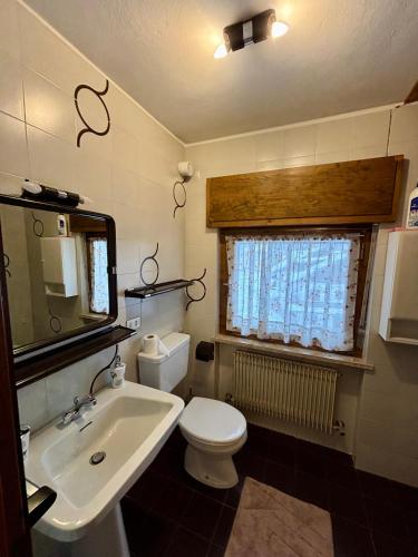 a bathroom with a sink and a toilet and a window at Pragma Apartments - Cupido's Alpine Nest in Bellamonte