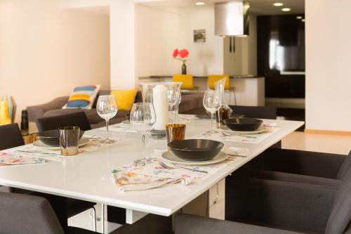 a white table with wine glasses and plates on it at Apartamento Vista Mar in Olhão