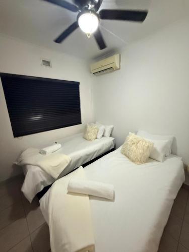 two beds in a room with a ceiling fan at SeaBreeze Sanctuary in Richards Bay
