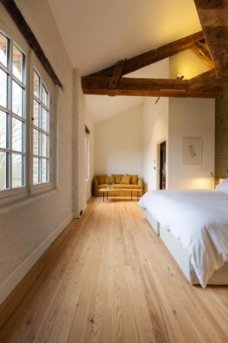 a bedroom with a large white bed and windows at Moulin de Cazaux-Savès in Cazaux-Savès