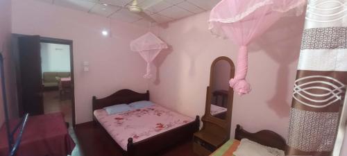 a small bedroom with a bed and a mirror at New Olina Gest and Restaurant in Wellawaya