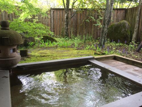 a pond in a garden with a wooden fence at 久住高原 赤川温泉スパージュ-Spaju in Taketa