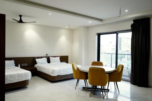 a hotel room with two beds and a table and chairs at Hotel Leena Inn in Jhālāwār
