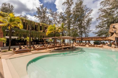 a pool at a resort with lounge chairs and palm trees at Café del Mar Phuket - Suite & Penthouse in Kamala Beach