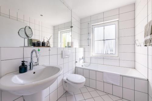 a white bathroom with a sink and a toilet at Inselhotel Rügen in Göhren