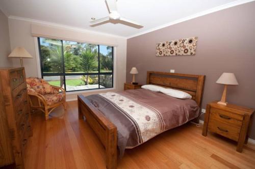 a bedroom with a bed and a chair and a window at Cambroe in Lakes Entrance