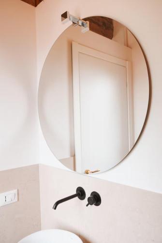 a bathroom with a round mirror above a sink at Tenuta La Macina in Polpenazze del Garda