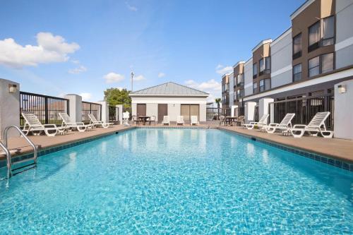a swimming pool with chairs and tables on a building at Country Inn & Suites by Radisson, Florence, SC in Florence