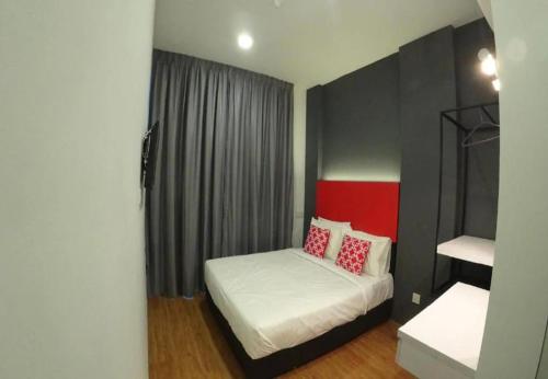 a small bedroom with a bed with red and white pillows at The Red Hotel in Bandar Saujana Putra