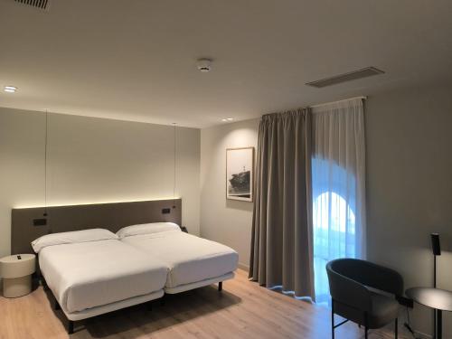a bedroom with a bed and a chair and a window at U-Hotel Aduana Ribadeo in Ribadeo