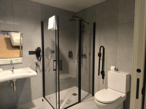 a bathroom with a shower and a toilet and a sink at U-Hotel Aduana Ribadeo in Ribadeo