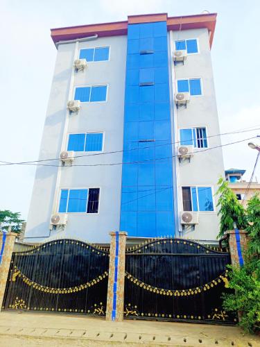 a building with blue windows and a black fence at MB California Guest House in Bonabéri