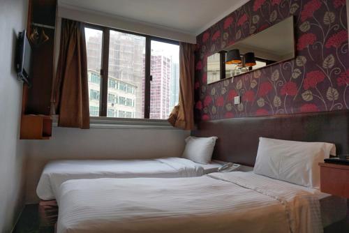 a hotel room with two beds and a window at Lander Hotel Prince Edward in Hong Kong