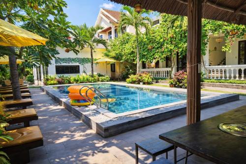 a swimming pool in a yard with a table and chairs at The Son Villa Hội An in Danang