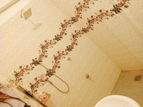 a shower with a plant on the wall of a bathroom at Mano Holiday Guest House in Kalkudah