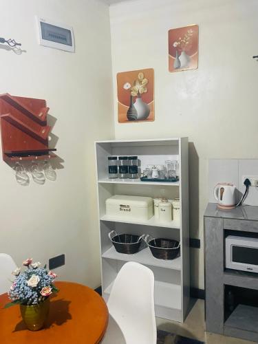 a kitchen with a table and a shelf with pots and pans at Fusion Apartments in Lusaka