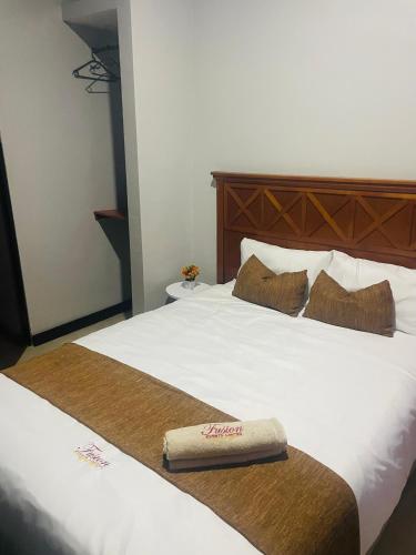 a hotel room with a bed with a towel on it at Fusion Apartments in Lusaka
