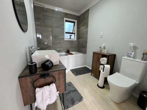 a bathroom with a sink and a toilet and a tub at Elephant View Homestead - Hydrangea Cottage in Plettenberg Bay