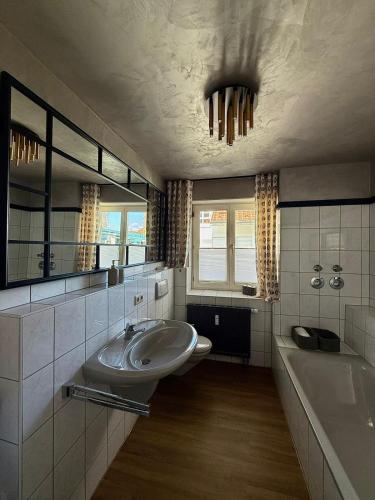 a bathroom with a sink and a tub and a toilet at CASAMA am See in Langenargen