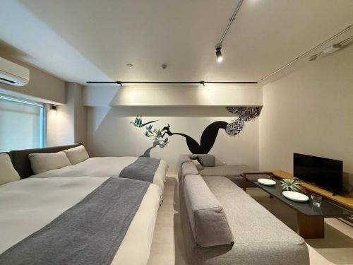 a bedroom with a bed and a couch and a tv at Origaminn 301 by b hotel - 5 mins Peace Park in Hiroshima