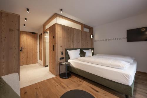 a bedroom with a large white bed and wooden walls at Hotel Ladinia in La Villa